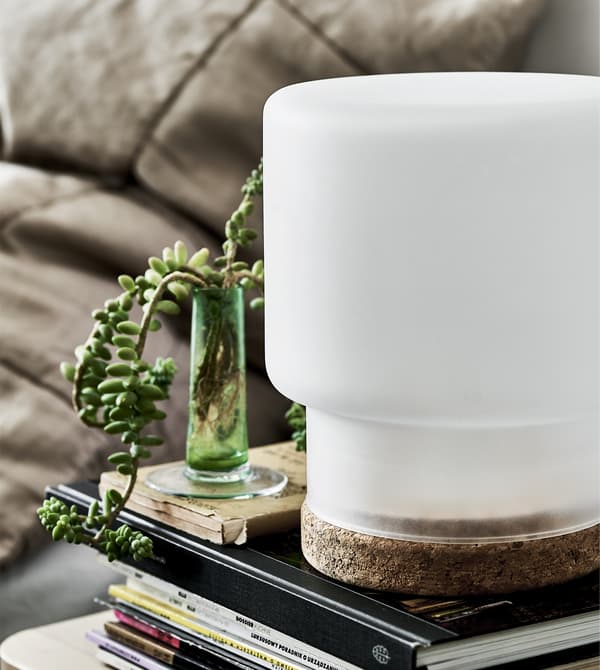 โคมไฟสีขาวพร้อมฐานไม้ก๊อกบนกองหนังสือ