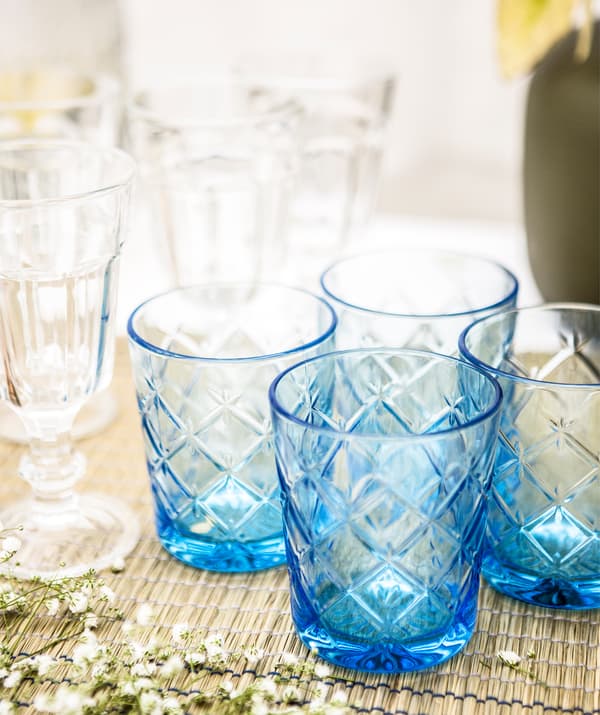 แก้วเจียระไนสีฟ้าและแก้วไวน์หลายใบบนผ้าคาดโต๊ะ