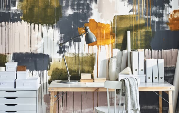 โต๊ะ, ลิ้นชัก และเก้าอี้ในโฮมออฟฟิศตั้งอยู่ตรงกำแพงที่ตกแต่งด้วยการหยดสีขนาดใหญ่หลากหลายสีสัน