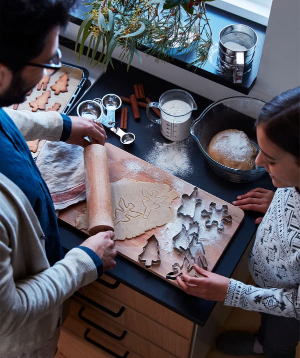 ผู้ชายและผู้หญิงยืนอยู่ข้างท็อปครัวที่เปรอะไปด้วยวัสดุที่ใช้อบขนมปังขิง