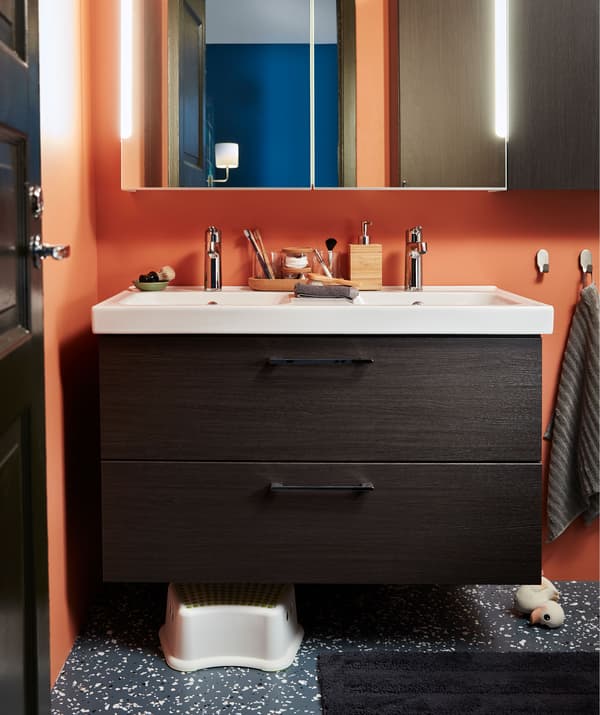 ส่วนของห้องน้ำที่มีตู้ตั้งอ่างล้างหน้าสองตู้พร้อมลิ้นชัก ตู้มีบานกระจกเงาอยู่เหนือขึ้นไป สตูลและตุ๊กตายางรูปเป็ดของเด็กอยู่ด้านล่าง