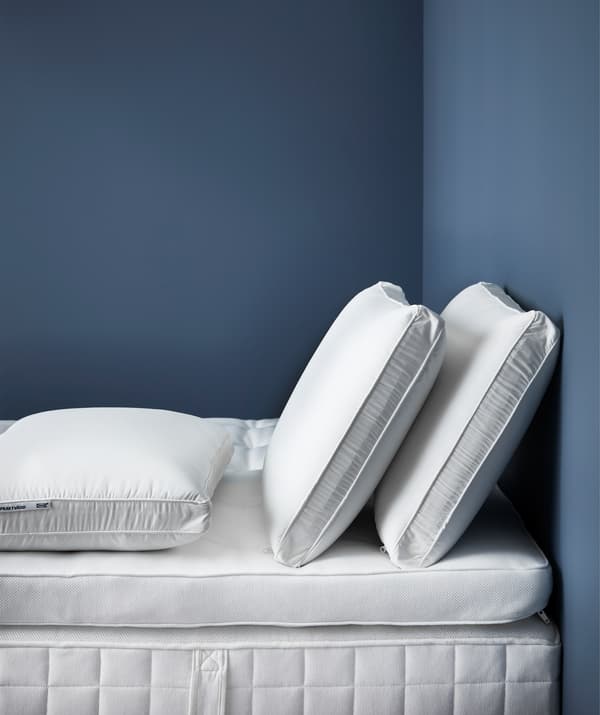 หมอนที่รองรับสรีระสำหรับคนนอนตะแคงสามใบบนฐานรองที่นอนที่มีเบาะเสริมที่นอนอยู่ด้านบน