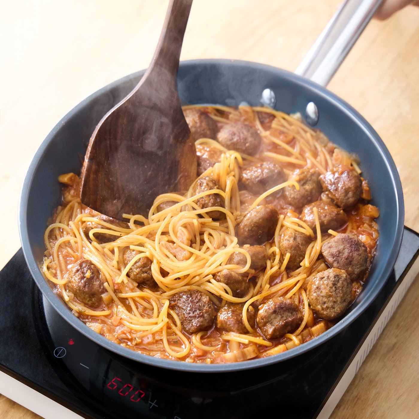 프라이팬에 미트볼과 소스가 담겨있고 파스타를 끓이고 있는 모습