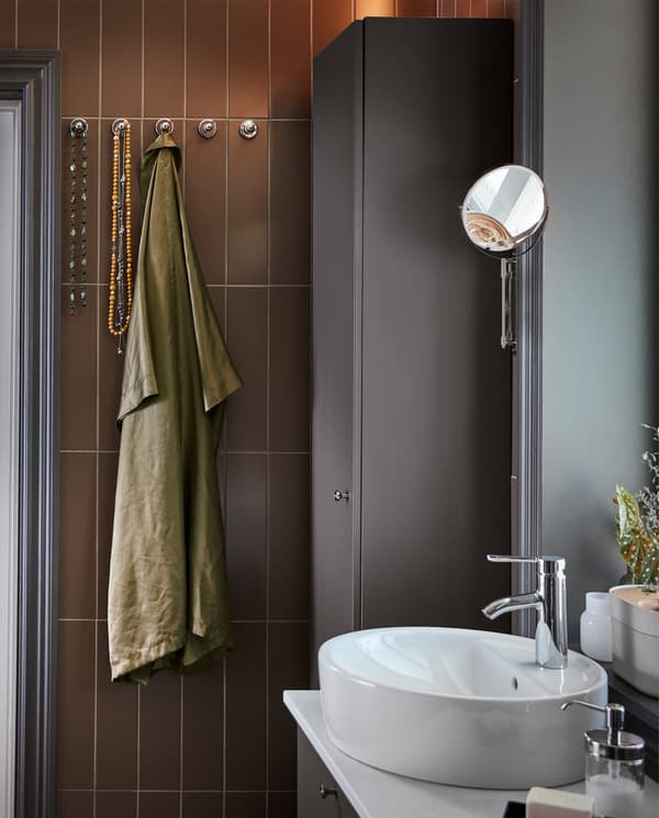 다크그레이/화이트 색상의 세면대/세면기, 다크그레이 색상의 키큰장과 크롬도금 처리된 벽고정 손잡이 다섯 개.