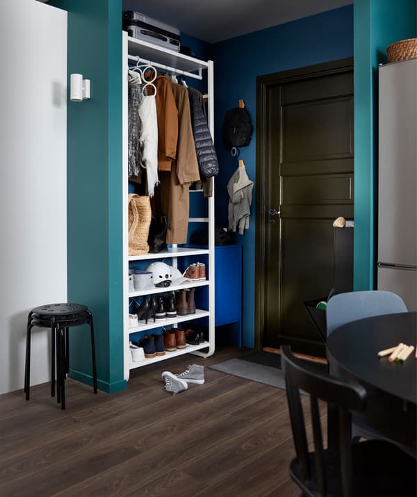 มุมของห้องที่ใหญ่กว่าใช้เป็นโถงทางเดิน ด้านข้างประตูหน้าเป็นชั้นวางมีที่เก็บของไร้บาน