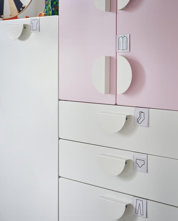 옷이 그려진 라벨 홀더가 화이트/페일 핑크 옷장 서랍과 도어에 부착되어 있는 모습.