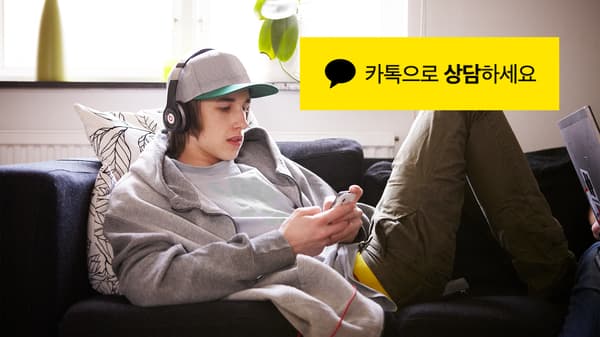 헤드폰을 끼고 소파에 앉아 휴대폰을 사용중인 남자의 모