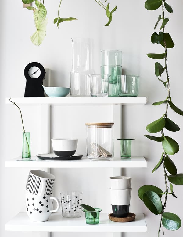 แก้วน้ำ แก้วมีหูจับ และกิ่งไม้ที่โชว์บนชั้นวางสีขาวสามชั้น
