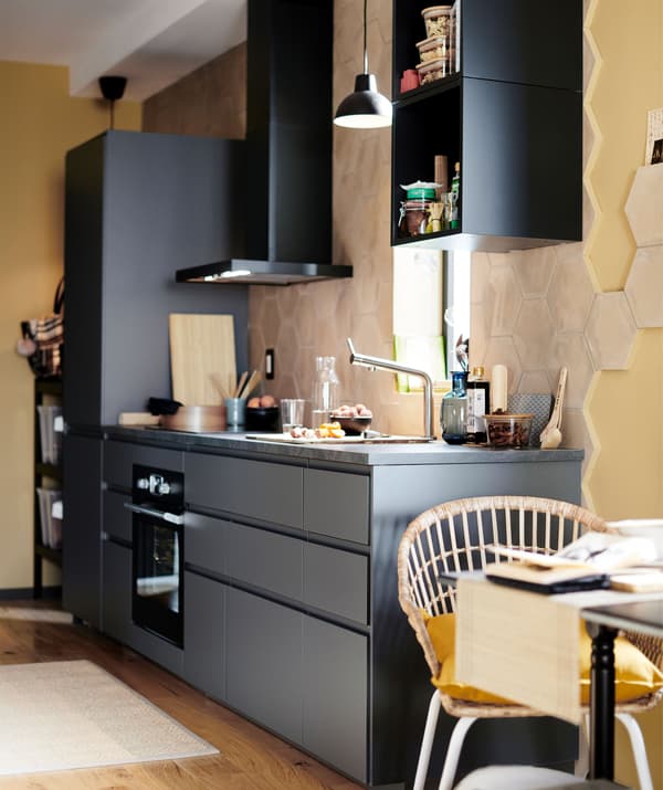 ห้องครัวผนังด้านเดียวสีดำพร้อมเครื่องดูดควันติดผนังในห้องที่ทาด้วยสีเหลืองอ่อน