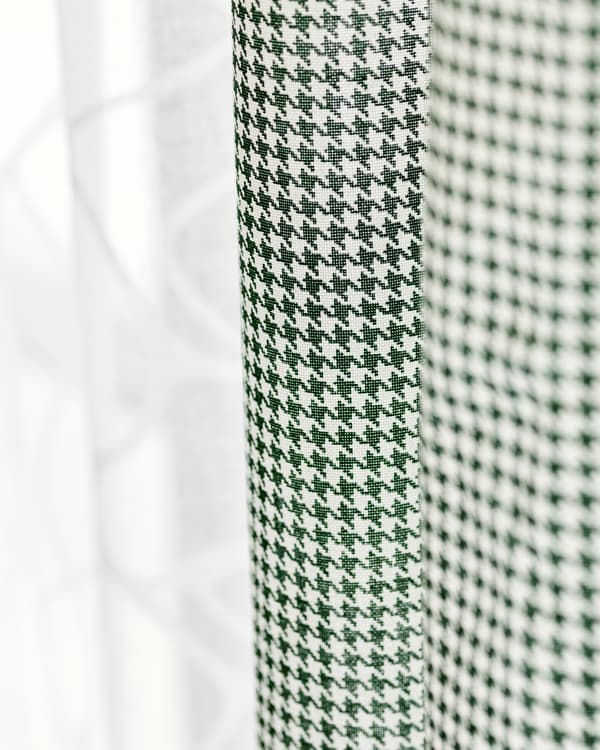 ม่านสองผืนแขวนอยู่ติดกัน ผืนหนึ่งเป็นผ้าฝ้ายโปร่งสีขาว อีกผืนเป็นลายตารางสีเขียวและสีขาว