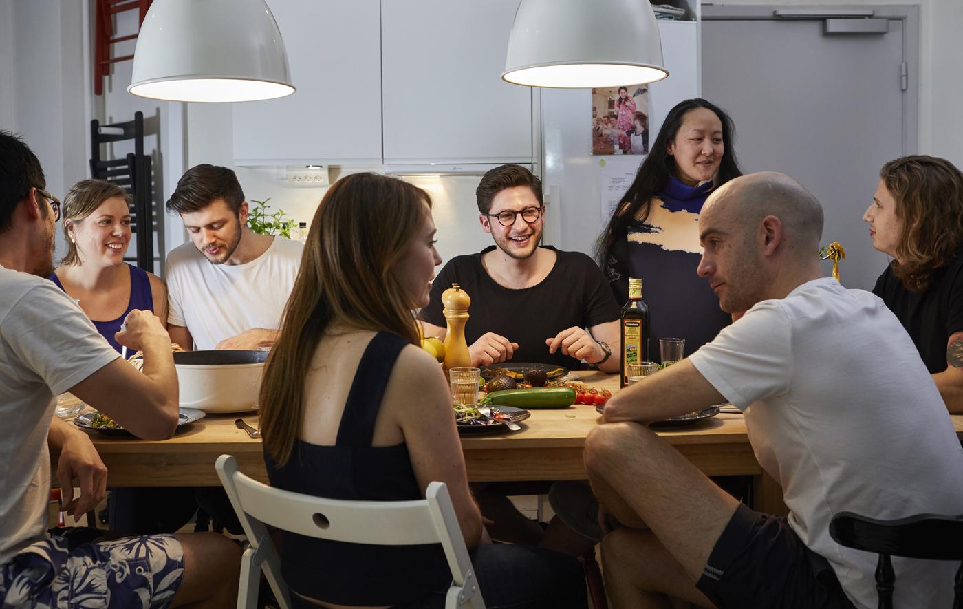 คนกลุ่มใหญ่กำลังรับประทานอาหารมื้อค่ำและคุยกันอยู่รอบๆ โต๊ะ