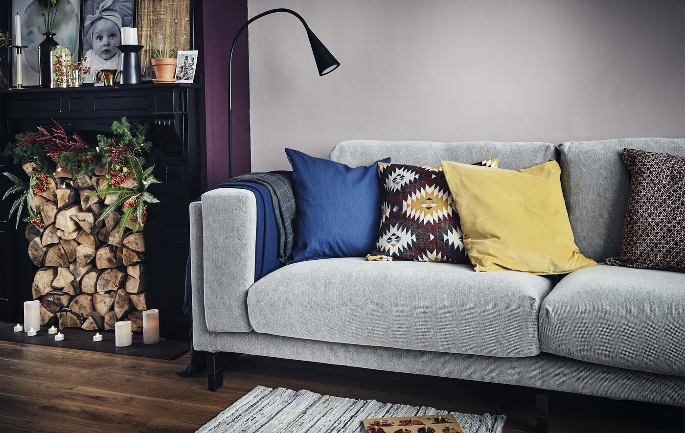 ห้องนั่งเล่นกับโซฟาสีเทา แสงไฟ และเตาผิงที่เติมฝืนไว้แล้ว