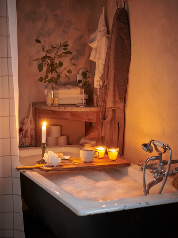 อ่างอาบน้ำที่มีฟองสบู่อยู่เต็ม มีเขียงพาดอยู่ที่ขอบอ่างทั้งสองข้างและมีเทียนและของใช้อื่น ๆ วางอยู่