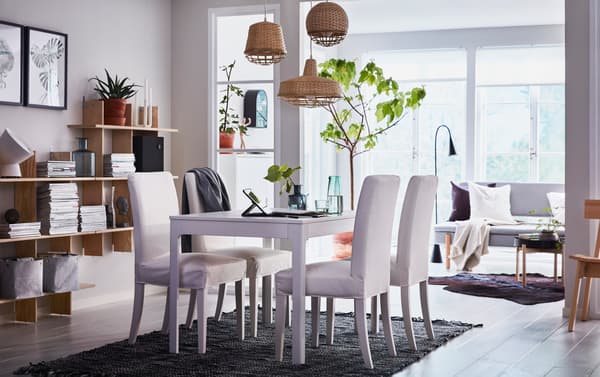 A beige, black and white dining area in an open-plan living space with white upholstered HENRIKSDAL chairs and EKEDALEN extendable table.