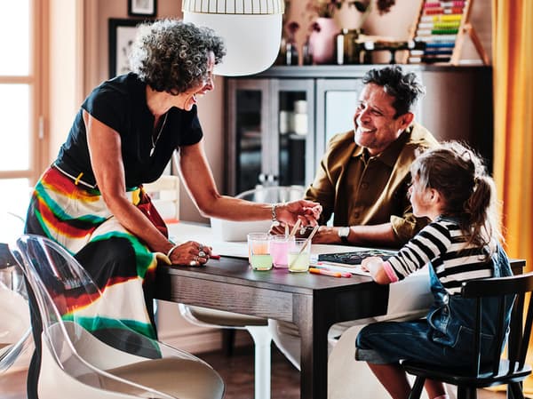 2 adults and 1 child sitting around a kitchen table