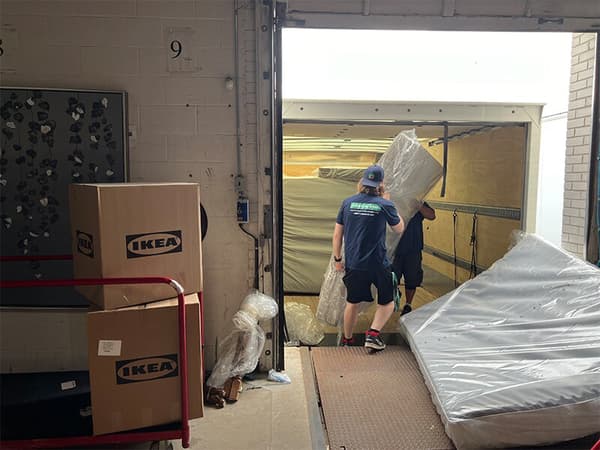 2 delivery workers unloading a mattress from a truck