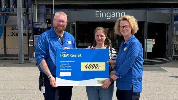 2 Frauen und ein Mann stehen vor dem IKEA Einrichtungshaus in Kaarst und halten gemeinsam einen Spendenscheck in Höhe von 4.000€ .