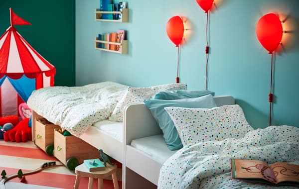 2 lits pour enfant SLÄKT posés en longueur devant un mur bleu turquoise