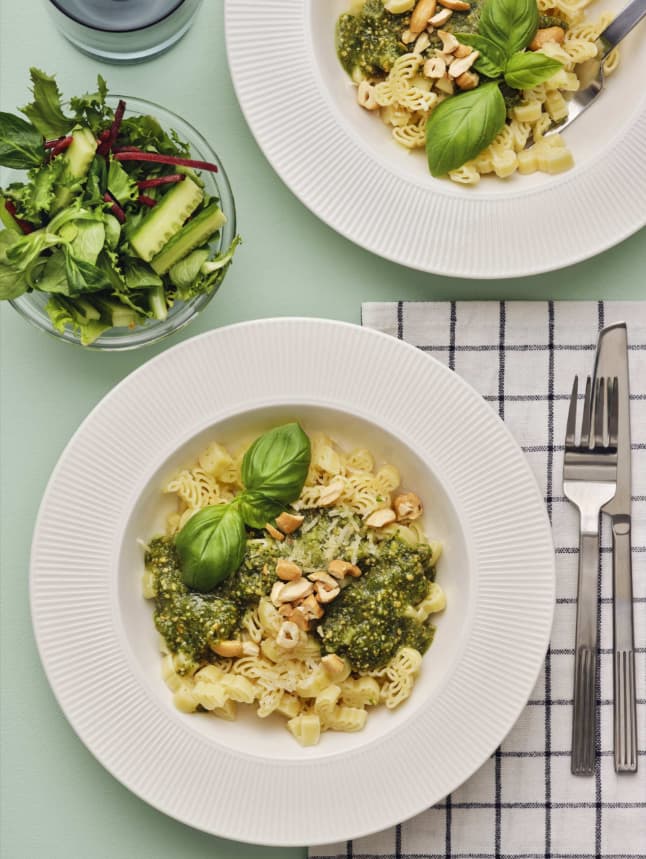 2 Teller gefüllt mit Pasta und grünem Pesto.