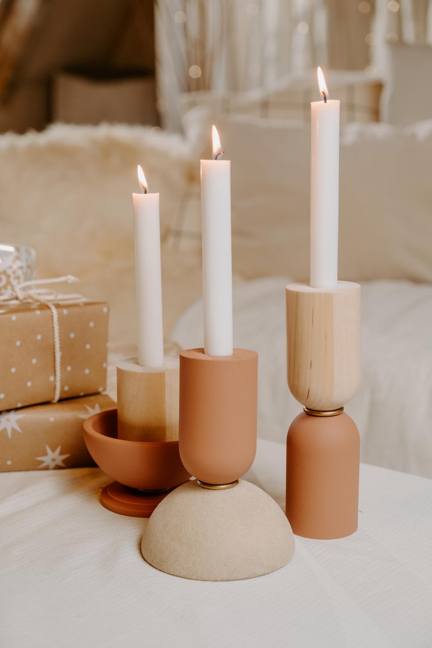 3 bougeoirs couleurs pastels avec les bougies allumées