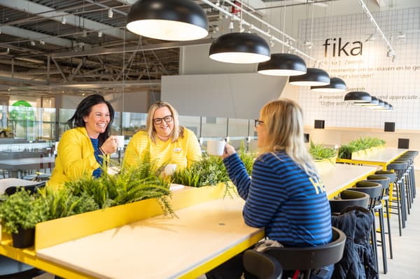 3 collaboratrices avec un café à la main autour d'une table 