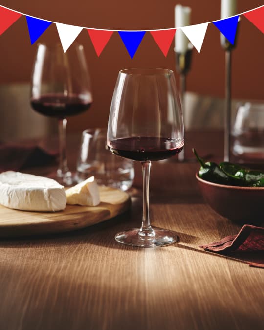 3 copas con vino tinto y al lado una tabla para picar con un queso.