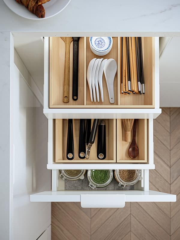 3 kitchen drawers that are open and are displaying bamboo interior organizers.