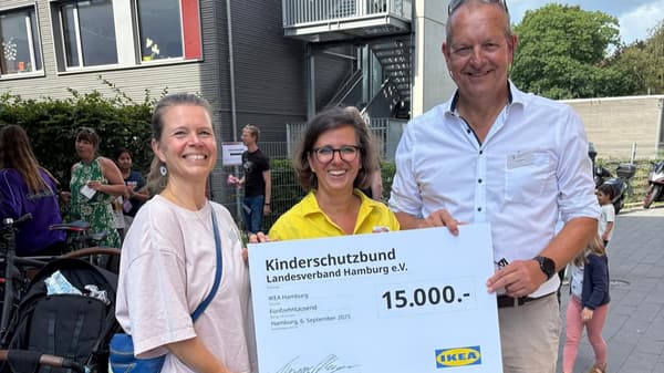 3 Menschen stehen zusammen und halten gemeinsam einen großen Scheck über 15.000 Euro hoch.