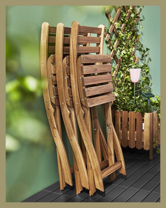 3 sillas de terraza de madera plegadas en una pared de un patio.