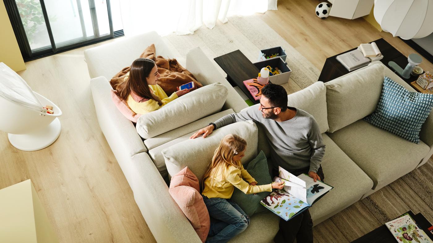 ผู้ชายและเด็กนั่งอยู่บนโซฟาเบด 3 ที่นั่ง VIMLE/วิมเล ที่ตั้งหันหลังชิดกับเก้าอี้นวมตัวยาว VIMLE/วิมเล ที่มีผู้หญิงนั่งอยู่