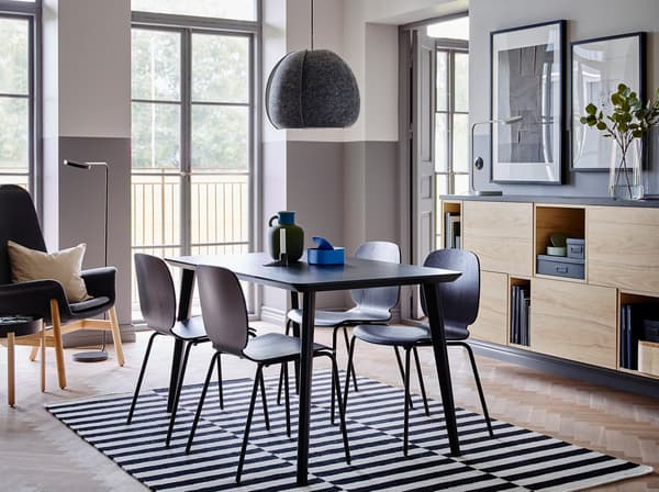 The quick to assemble LISABO table and SVENBERTIL chairs in black make an elegant combination in the centre of a room with half grey, half white walls and open and closed storage in ash.