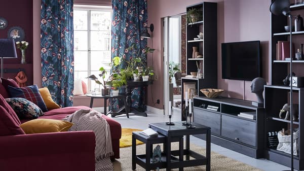 โซฟา 4 ที่นั่งสีแดงเข้ม GRÖNLID/เกรินลีด และตู้ทีวีสีน้ำตาลเข้ม HAVSTA/ฮาฟสต้า ในห้องนั่งเล่นที่มีผนังสีชมพูเข้ม