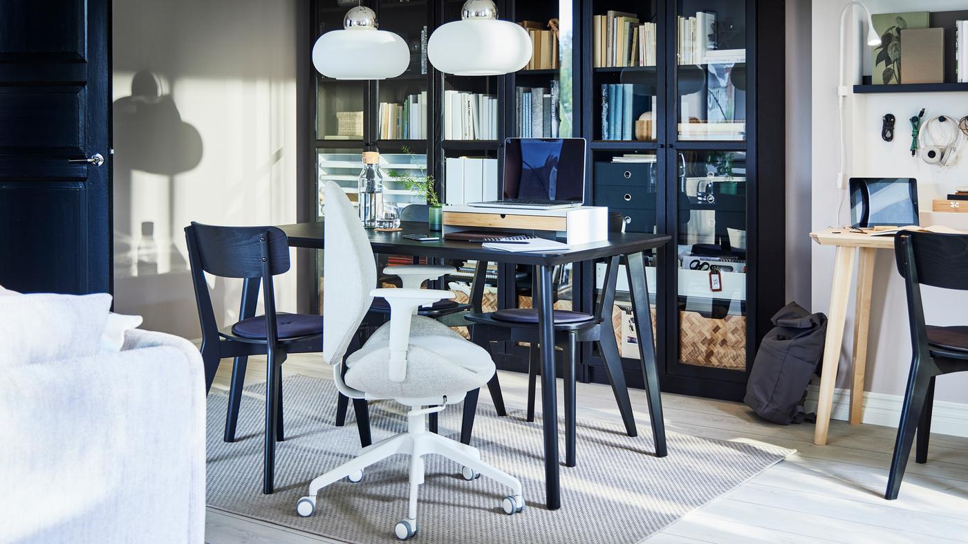 유리도어 책장 앞 4개의 의자에 둘러싸인 블랙 LISABO 리사보 식탁 위에 노트북을 놓고 업무 공간으로 꾸민 모습.