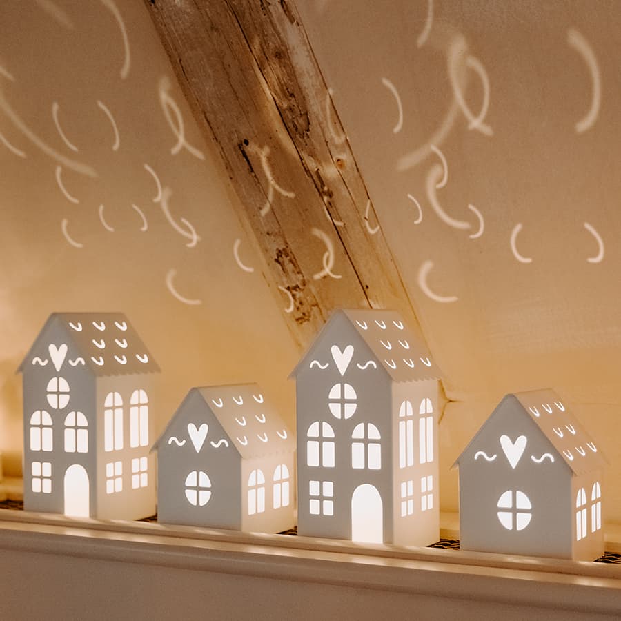 4 petites maisons décoratives lumineuses posées sur un rebord de meuble