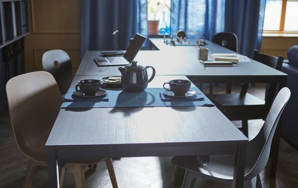 4 tables are arranged in a zigzag formation to accomodate different activities like chess, homework, and teatime.