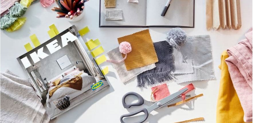 A copy of the 2021 IKEA Catalog on a desk with fabric and scissors- linking to Newsroom article about the 2021 IKEA Catalog.