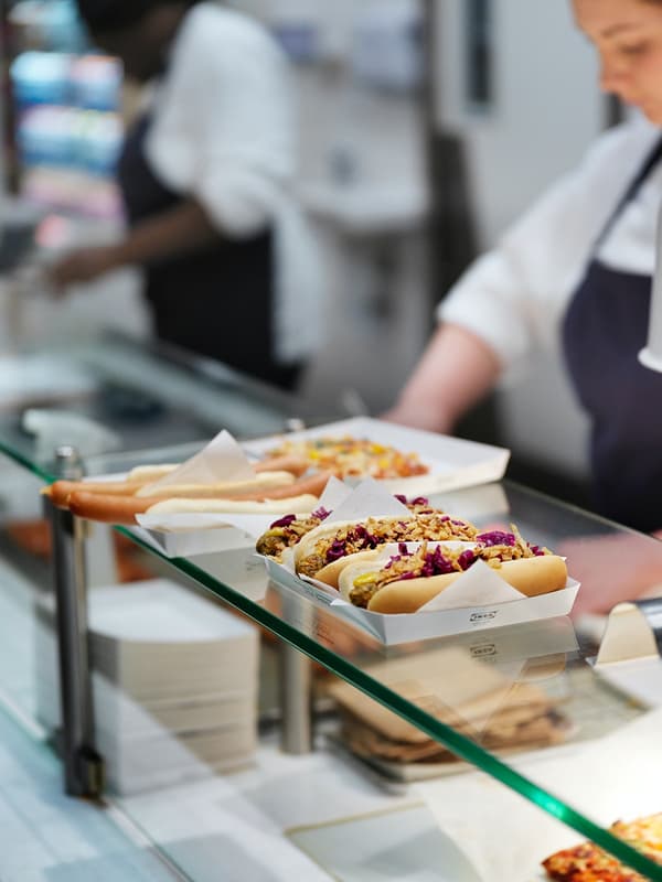 5 hot dogs empacados para llevar sobre un meson de vidrio de un Bistró IKEA. 