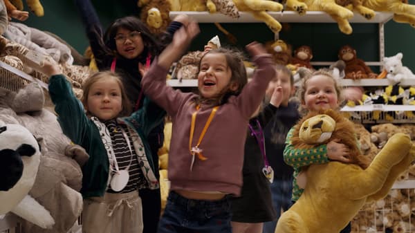 5 kinderen staan tussen knuffels en steken enthousiast hun armen in de lucht