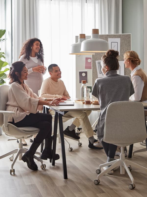 5 people in a meeting, sitting around a desk and sitting on IKEA desk chairs