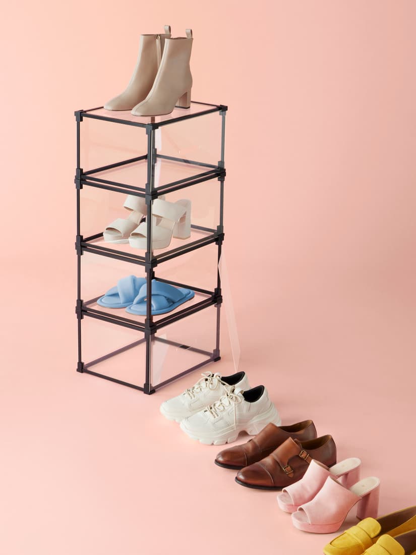 7 párů různych bot. 4 páry jsou na růžové podlaze vedle sebe, další 2 v přeledných boxes a černým rámem a poslední pár na vrchu boxů.