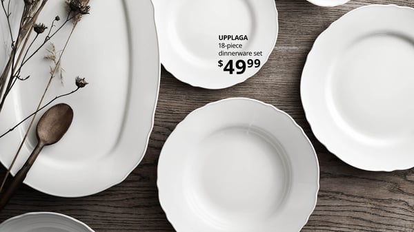 A dining table with white IKEA 365+ and UPPLAGA plates. UPPLAGA 18-piece dinnerware set, $49.99, linking to product page.
