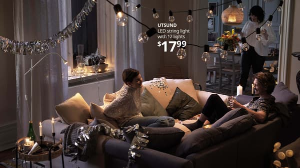 Three people celebrating the holidays in a living room. UTSUND LED string light with 12 lights, $17.99