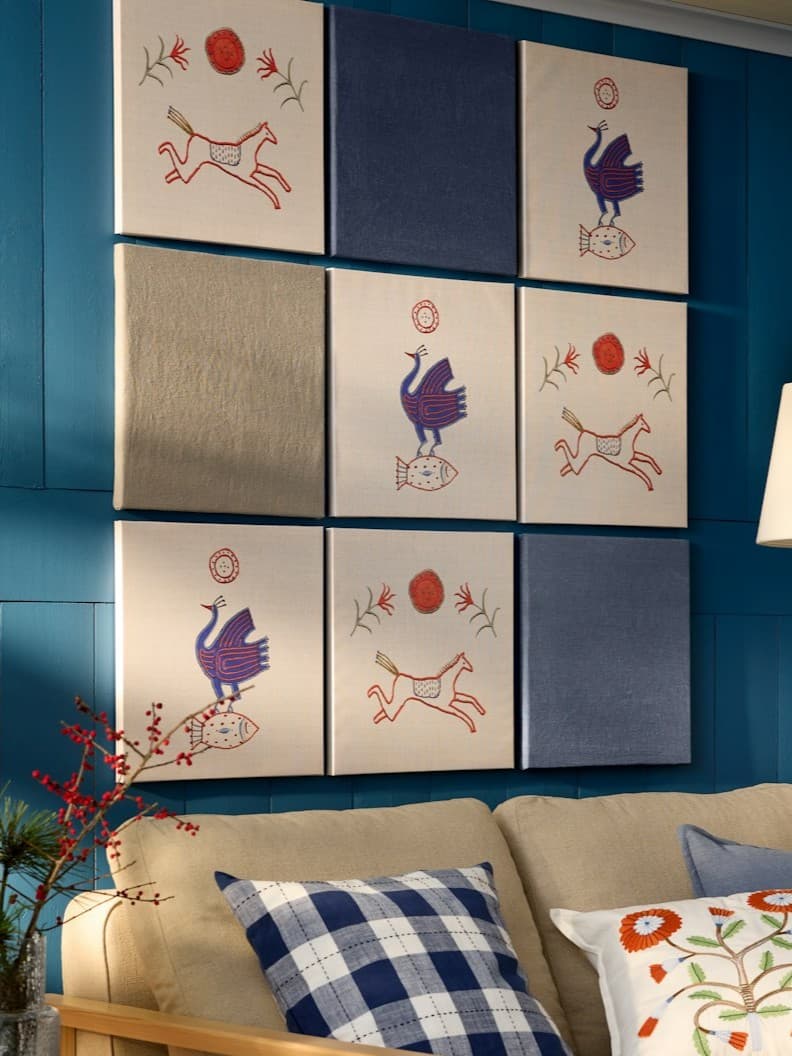 9 obrazów wiszących na niebieskiej ścianie nad sofą.