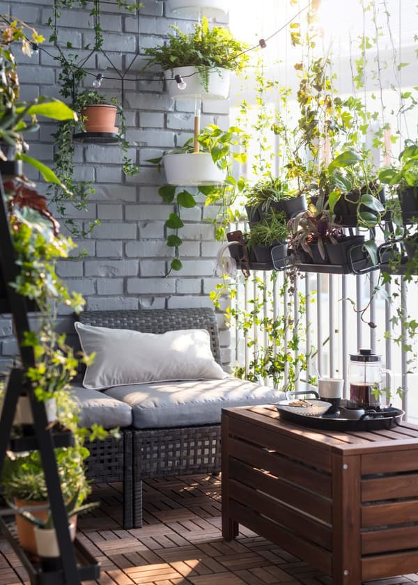  92/5000 Zelená oáza vytvorená na balkóne z vonkajšej sedačky, závesných kvetináčov a stojanov na rastliny.