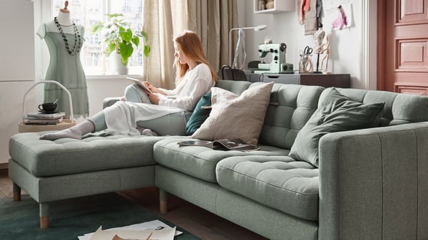 pokój dzienny, kobieta siedząca na jasnozielonej sofie LANDSKRONA