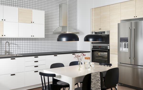 A kitchen with doors in white and light ash effect, two black pendant lamps, a white table and black chairs.