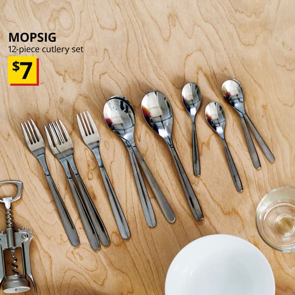 A 12-piece MOPSIG cutlery set placed on a dining table with a white OFTAST bowl at the bottom right corner of the image. Text on the top left of the image reads: MOPSIG,12-piece cutlery set. Price: $7. 