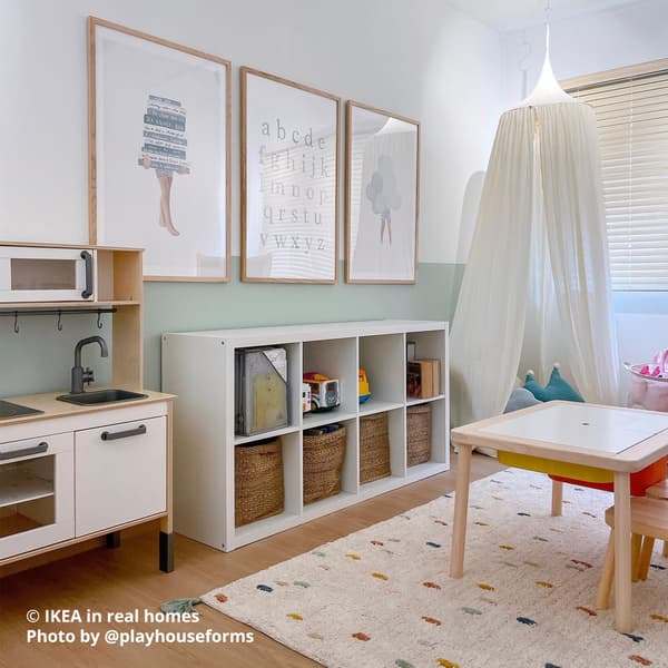 A 2x4 KALLAX shelf storing arts and craft materials. Beside it is a DUKTIG play kitchen. The wall is decoraed with pciture frames, one containing the alphabet. Photo by instagrammer @playhouseforms for IKEA in real homes ©