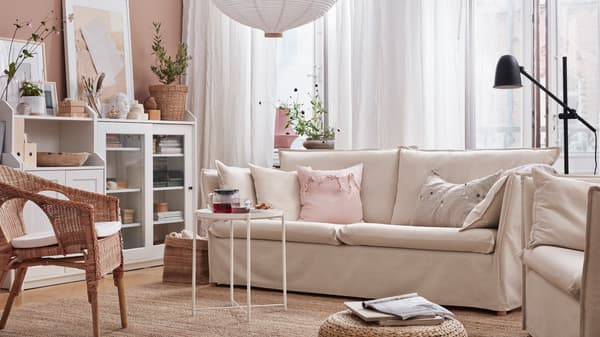 A 3-seat sofa, a flatwoven rug, a rattan armchair with cushion, a glass-door cabinet and a cabinet with 2 doors.