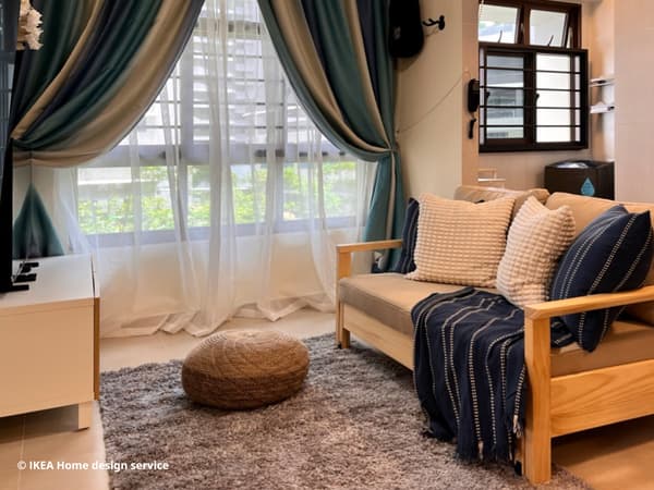 A 45 degree angle shot of the homeowner's living room showcasing a white BESTÅ TV bench with oak veneer doors, medium grey STOENSE rug, a beige SANDARED pouffe and a naggen beige/pine TORNSBORG 2-seat sofa-bed. 